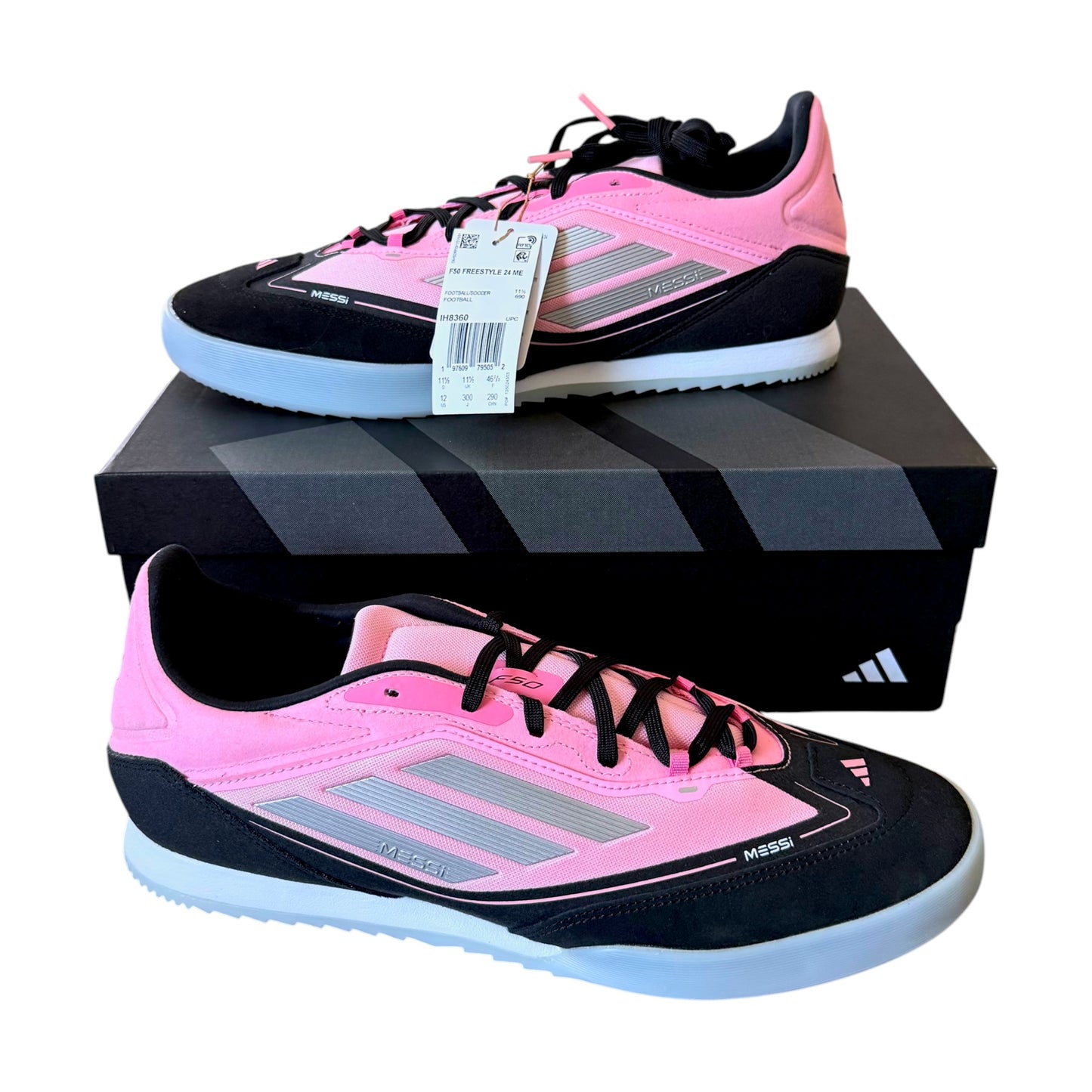 A pair of Adidas soccer cleats in pink and black, displayed with their black Adidas shoebox on a white background.