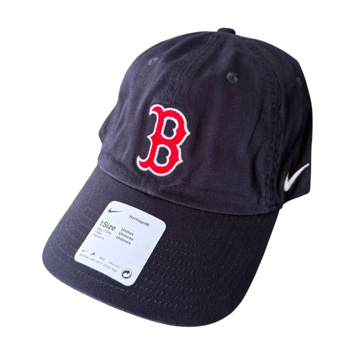 A navy blue baseball cap with a red embroidered Boston Red Sox 'B' logo on the front, a white Nike swoosh on the side, and a white size tag attached to the brim, shown against a plain white background.