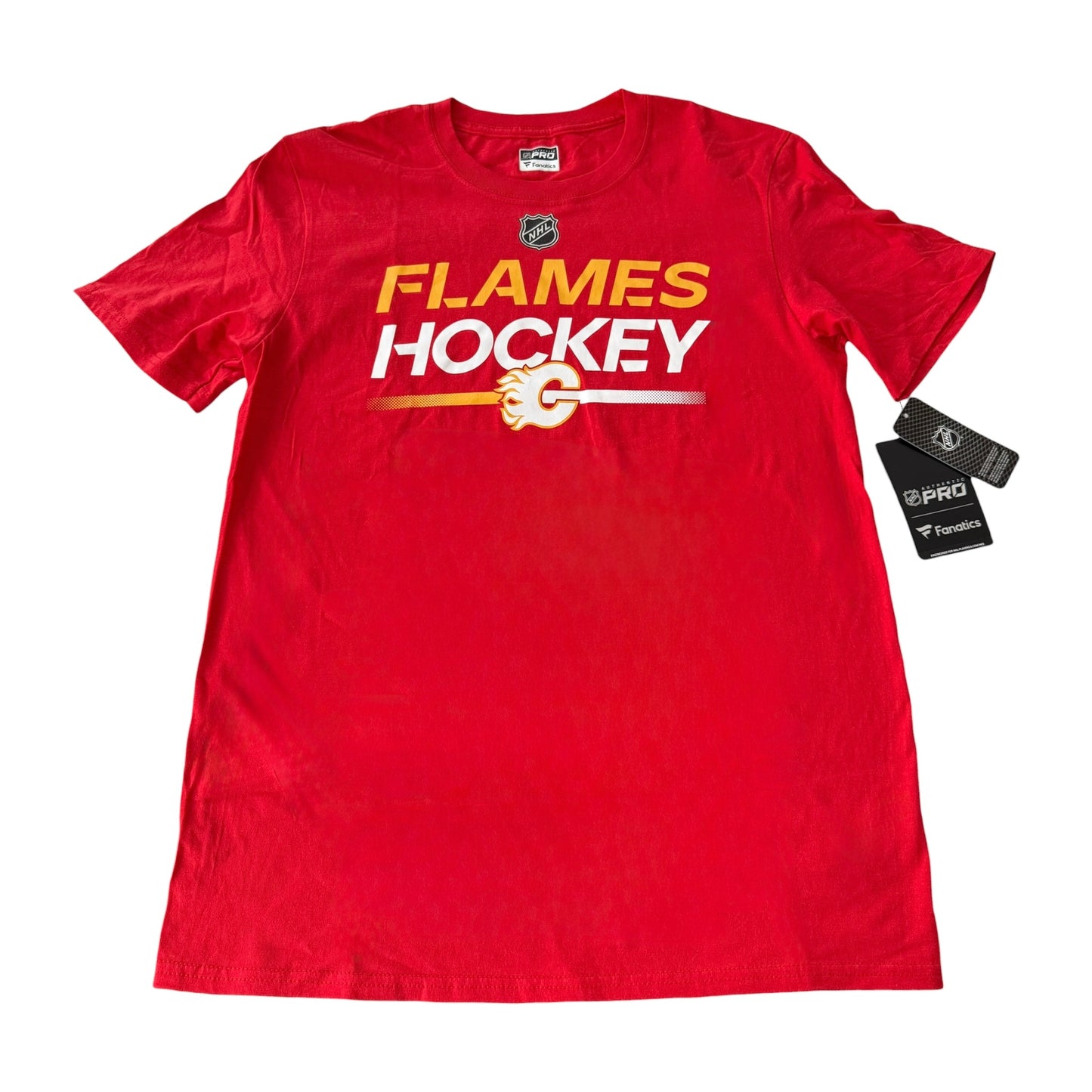 A red short-sleeve T-shirt with 'FLAMES HOCKEY' printed across the chest in yellow and white, featuring a hockey stick graphic and Calgary Flames logo. The shirt is displayed flat on a white background with two hang tags attached.