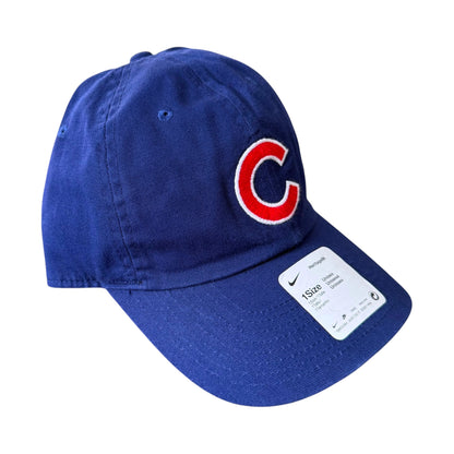 A royal blue baseball cap featuring a red embroidered 'C' logo with a white outline on the front, and a white Nike size tag attached to the brim.