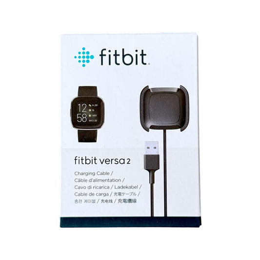 Fitbit Versa 2 charging cable and charging dock in its original white retail packaging, featuring the Fitbit logo and product illustrations.