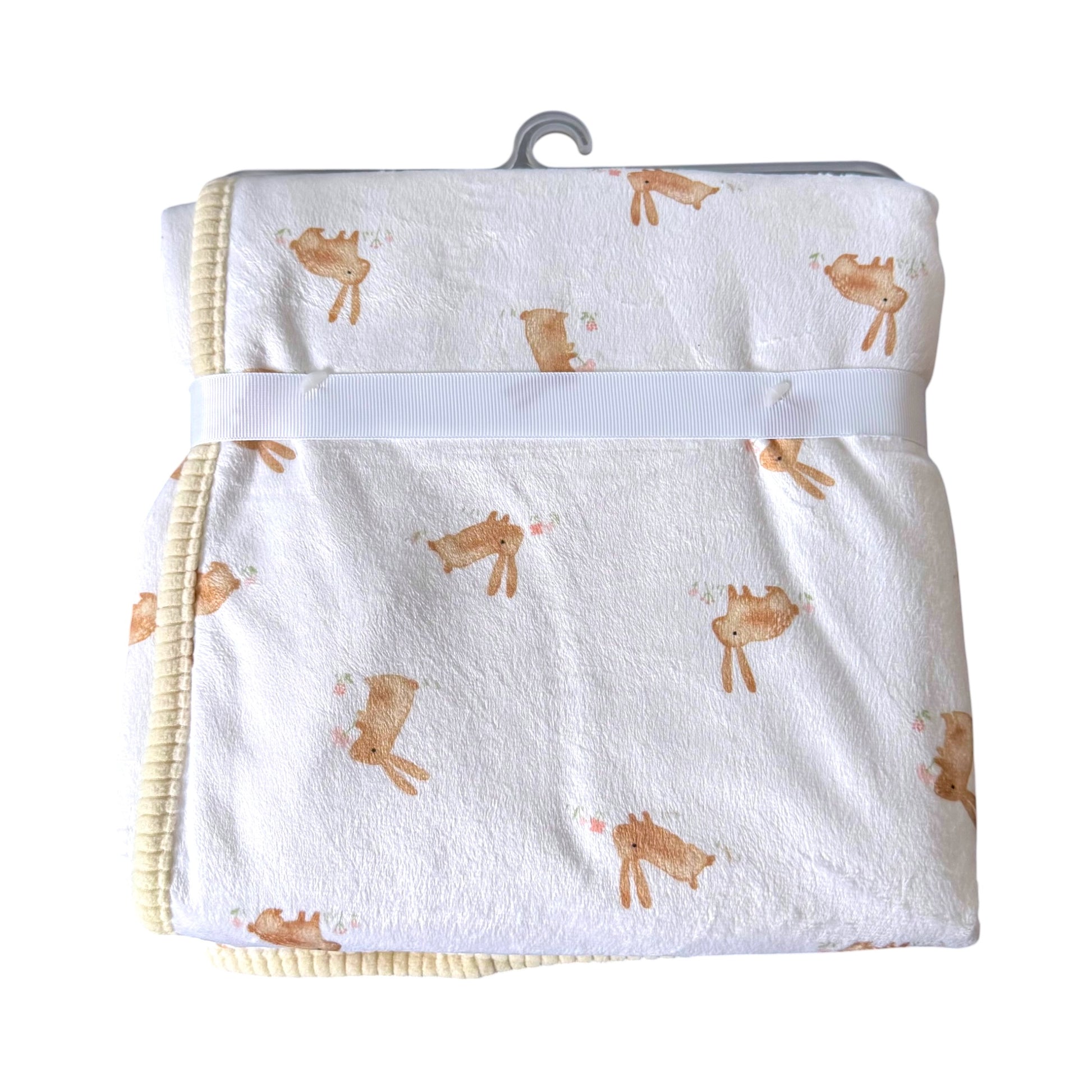 A folded white Gerber baby blanket with a light brown bunny pattern, wrapped in a white ribbon and hanging from a gray plastic hook.