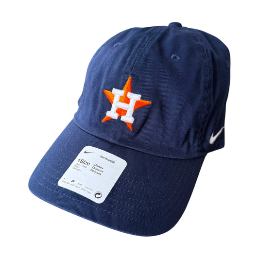 A navy blue Nike baseball cap with an embroidered orange and white Houston Astros 'H' logo on the front and a white Nike swoosh on the side. The cap is shown with its original white retail sticker on the brim, set against a plain white background.