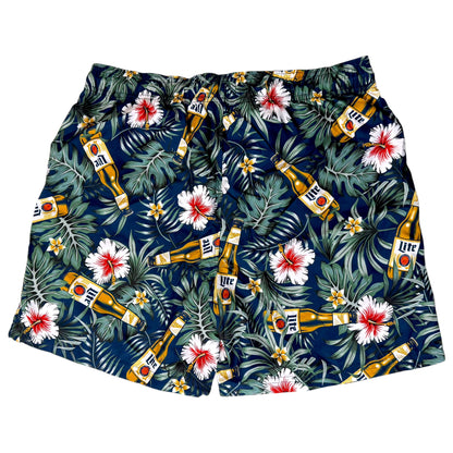 A pair of men's swim trunks featuring a dark navy blue tropical print with green palm leaves, white hibiscus flowers with red centers, and multiple Miller High Life beer bottles scattered throughout the pattern.