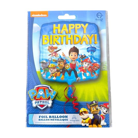 A packaged Paw Patrol foil balloon on a white background. The balloon is shaped like the Paw Patrol skyline and features the characters in the center with 'HAPPY BIRTHDAY!' printed in yellow.