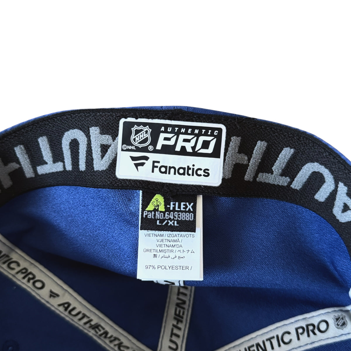 Close-up of the interior of a blue hockey cap, showing the black Authentic Pro Fanatics elastic band and interior labels.