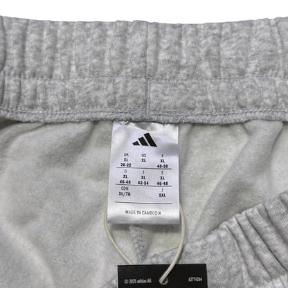 Close-up of the inside waistband of light gray heathered shorts, showing the white Adidas size tag and black hangtag.