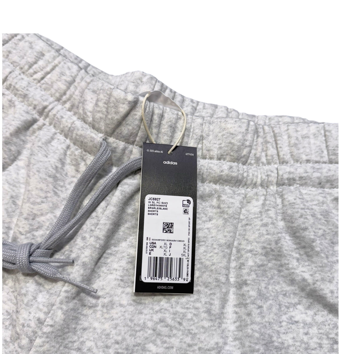 Close-up of light heather gray shorts with a gray drawstring and an attached black Adidas hangtag, photographed against a white background.