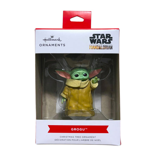 Hallmark Star Wars The Mandalorian Grogu Christmas tree ornament wearing a tan robe with one hand raised in its window display box.