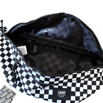 A Vans checkered bag shown open, displaying its black and white checkerboard exterior and interior lining with a Vans logo patch on the front.